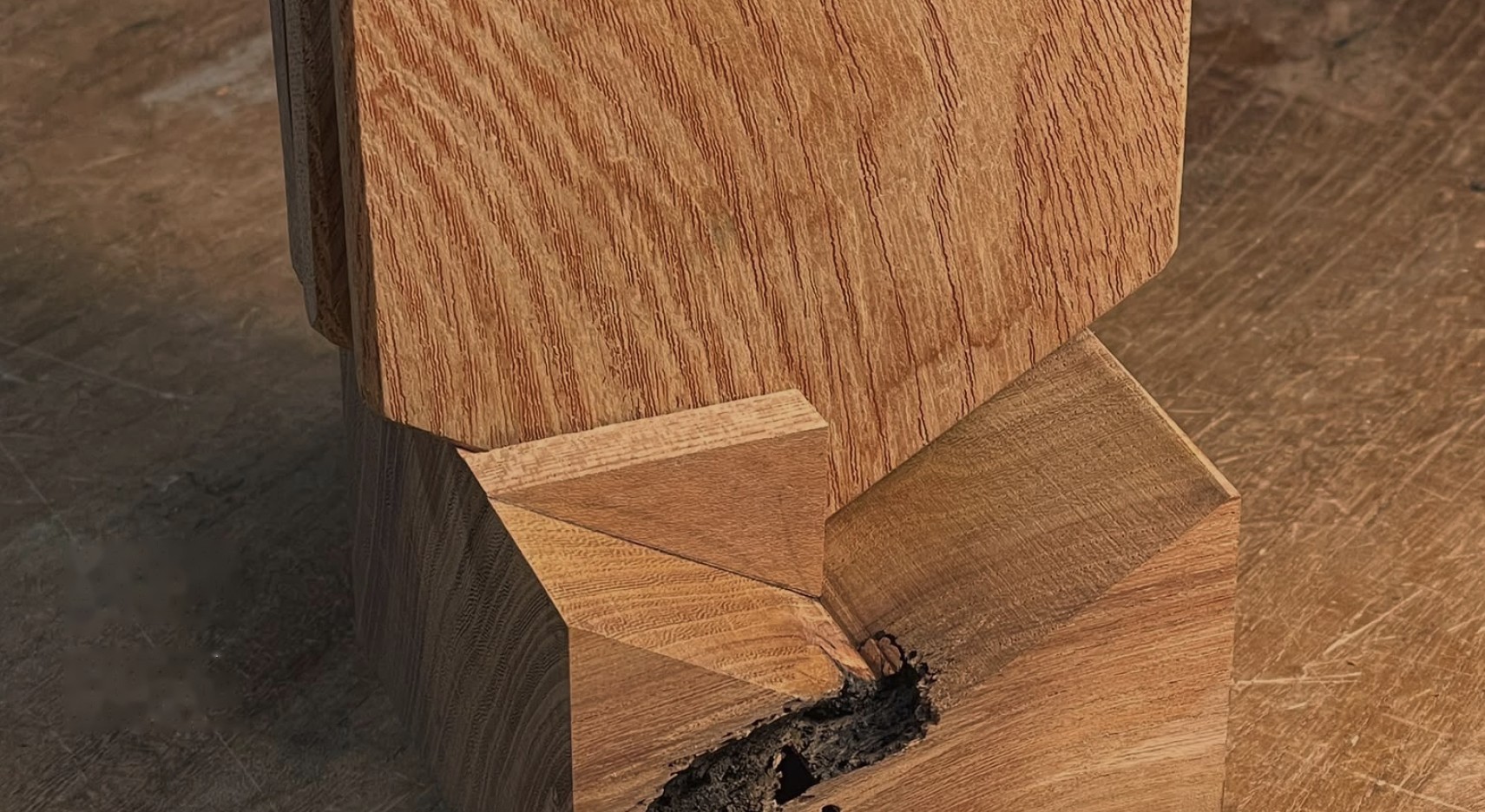close-up of a carved oak piece resting on a scarred workbench